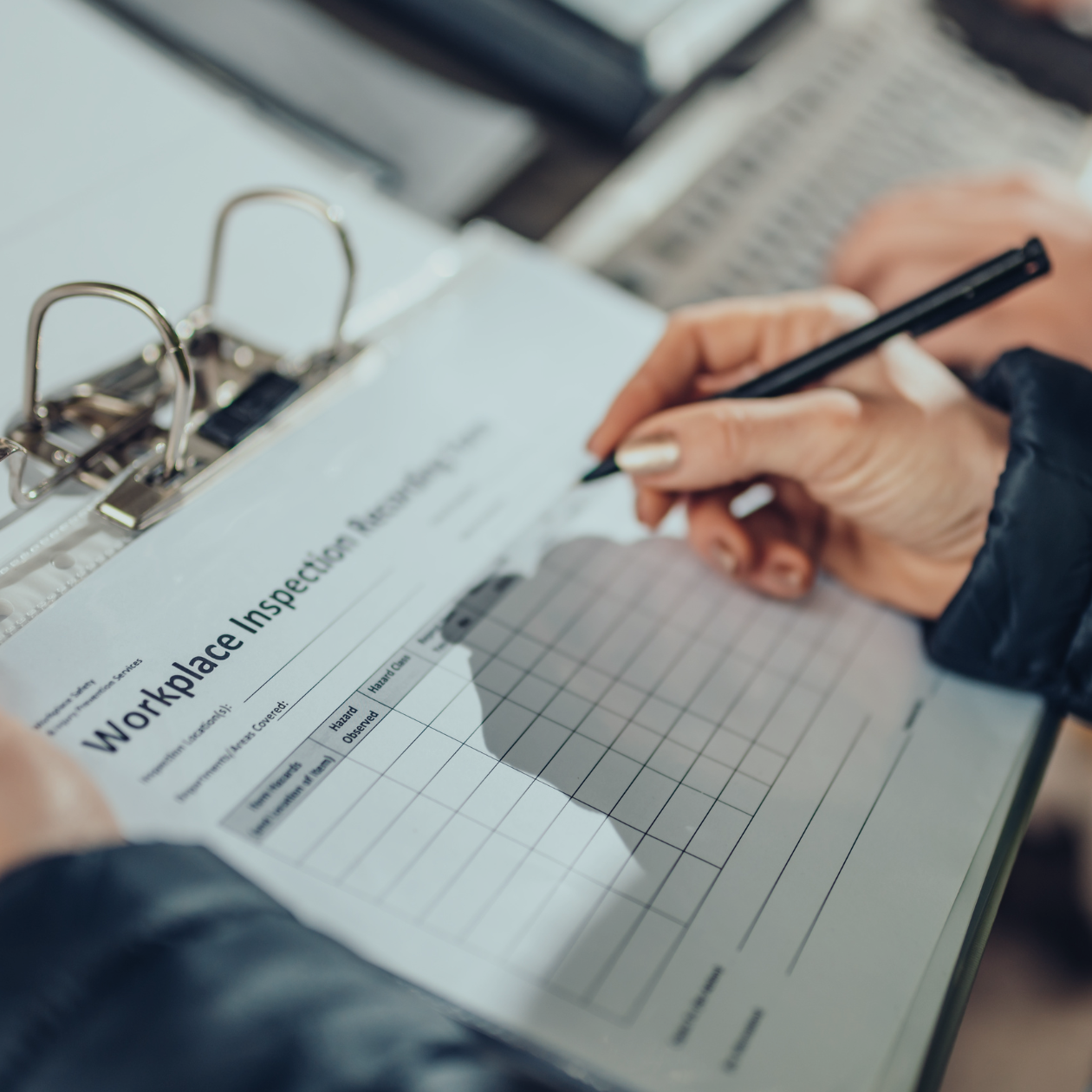 Person filling out a 'Workplace Inspection Checklist' with a pen.