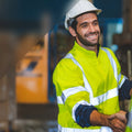 Two construction workers shaking hands with a blurred background