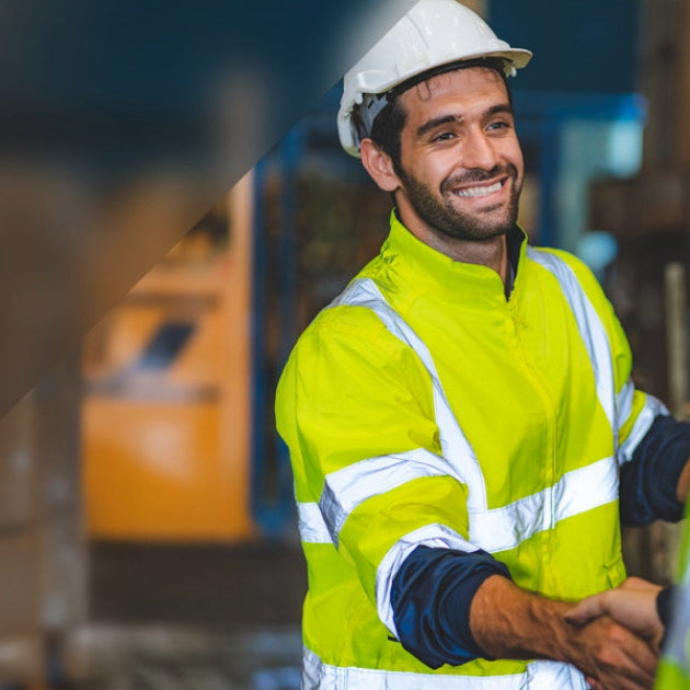 Two construction workers shaking hands with a blurred background