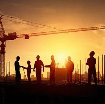Silhouettes of construction workers with a crane and sunset in the background